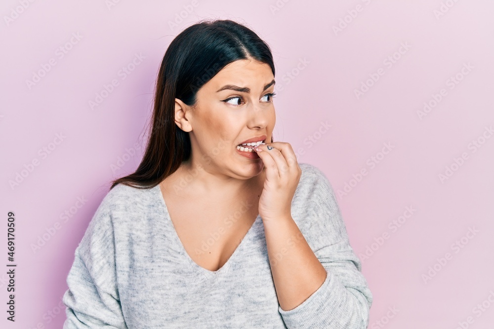 Young hispanic woman wearing casual clothes looking stressed and nervous with hands on mouth biting nails. anxiety problem. Young hispanic woman wearing casual clothes looking stressed and nervous with hands on mouth biting nails. anxiety problem.