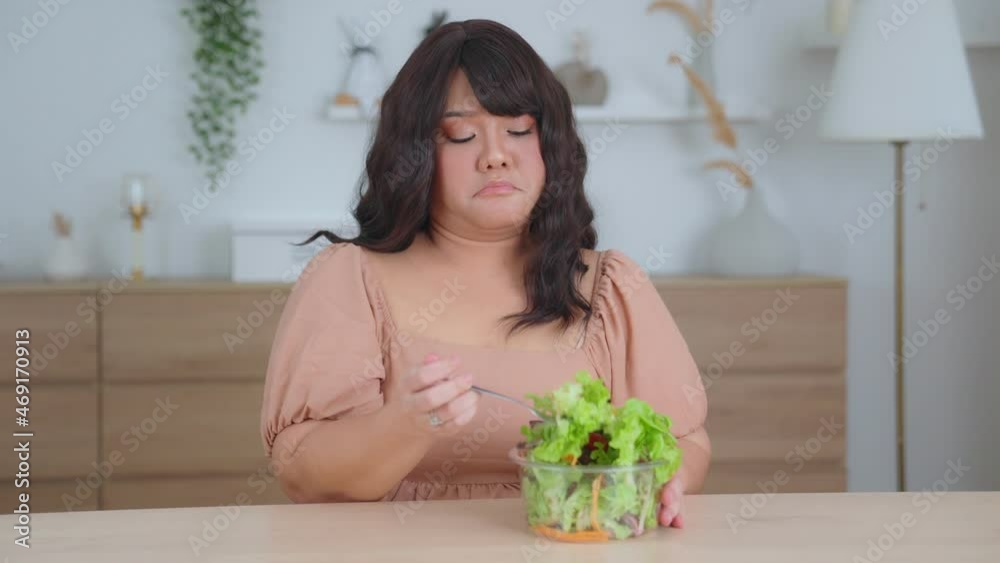 Asian woman oversize big chubby girl not enjoying eat vegetables and salad. Tired of eating food repeatedly or healthy food that doesn't taste good. overweight girl with Diet and weight loss concept. Asian woman oversize big chubby girl not enjoying eat vegetables and salad. Tired of eating food repeatedly or healthy food that doesn't taste good. overweight girl with Diet and weight loss concept.
