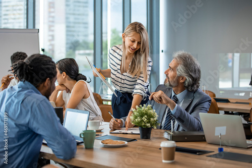 Young designer giving some new ideas about project to his partners in conference room. Business people discussing over new business project in office. Business People Working in The Office