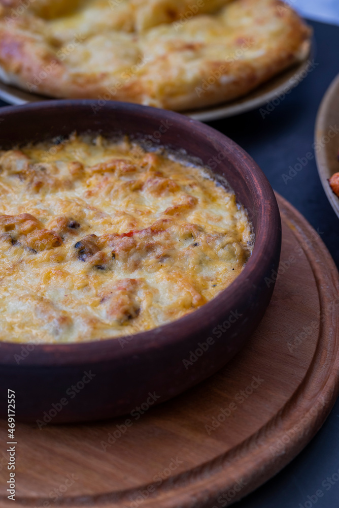 baked suluguni cheese with tomatoes of national Georgian cuisine in earthenware on ketsi