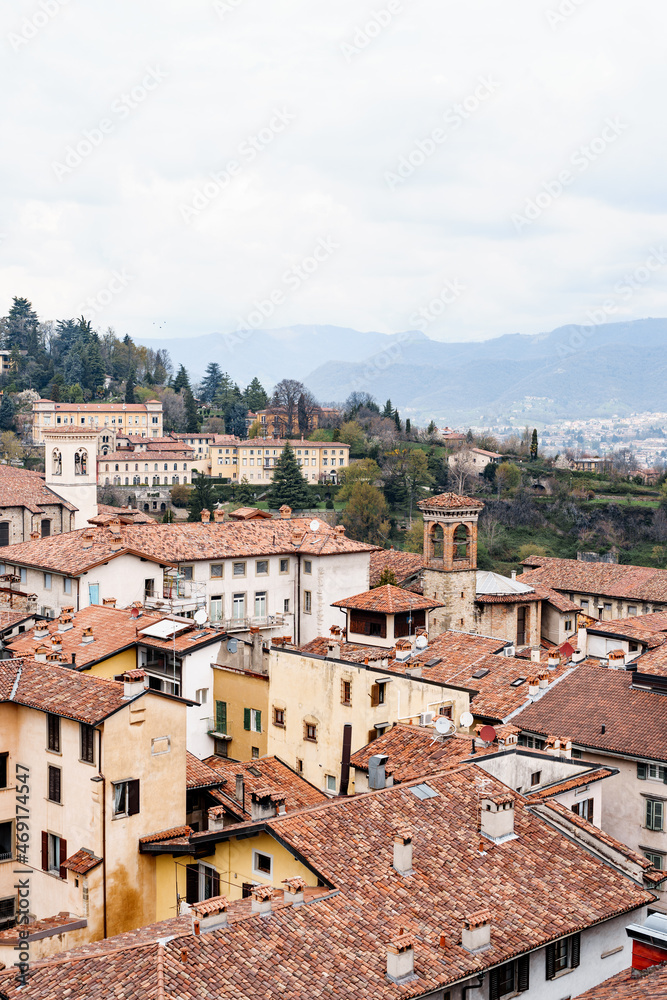 Tiled roofs of the old houses of Bergamo against the backdrop of the mountains. Italy