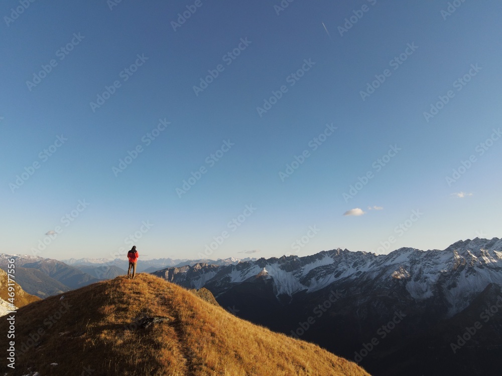 Man stands on a hill and in the background are the Alps