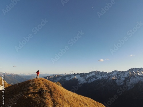 Fototapeta Naklejka Na Ścianę i Meble -  Man stands on a hill and in the background are the Alps