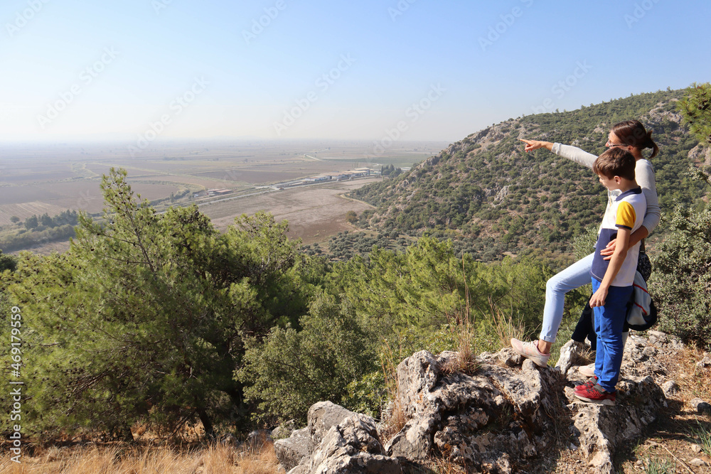 Obraz premium tourist family mother and son looking to the beautiful valley in the mountains