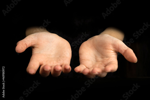Empty hands with empty palms up isolated on a black background