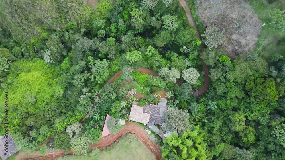A High Angle bird's eye view of houses that sit along side a red rocky road on a mountainous range A High Angle bird's eye view of houses that sit along side a red rocky road on a mountainous range