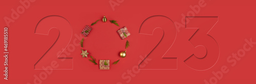 2023 New Year banner. Flat lay of Christmas decoration and Gift boxes on red background.  New Year greeting card or party invitation. Top view.