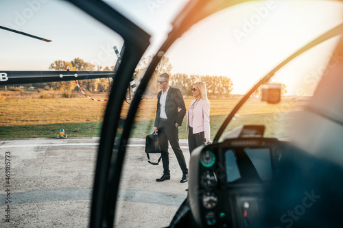Wealthy young business couple is preparing to use their own private chopper or helicopter to travel on vocation or business meeting. © hedgehog94