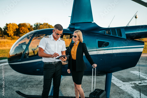 Obraz na płótnie Attractive middle age business woman standing on airport and using private air transport chopper or helicopter to travel to a business meeting