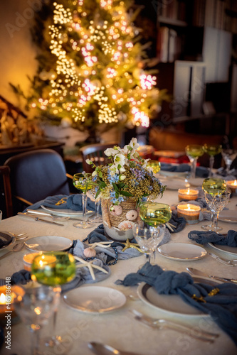 Christmas dinner table and lit Christmas tree