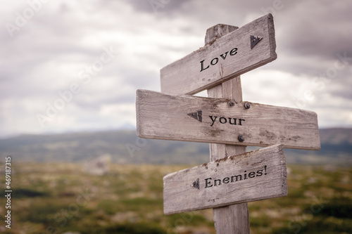 love your enemies text on wooden sign outdoors in nature. Religious and christianity quotes.