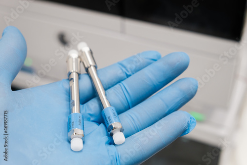Small HPLC 50 mm columns for separation compounds in laboratory worker hand in rubber glove. Fast high performance liquid chromatography analysis in chemical and microbiological laboratory. Clinical