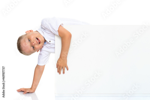 A little boy is looking from behind an empty banner.