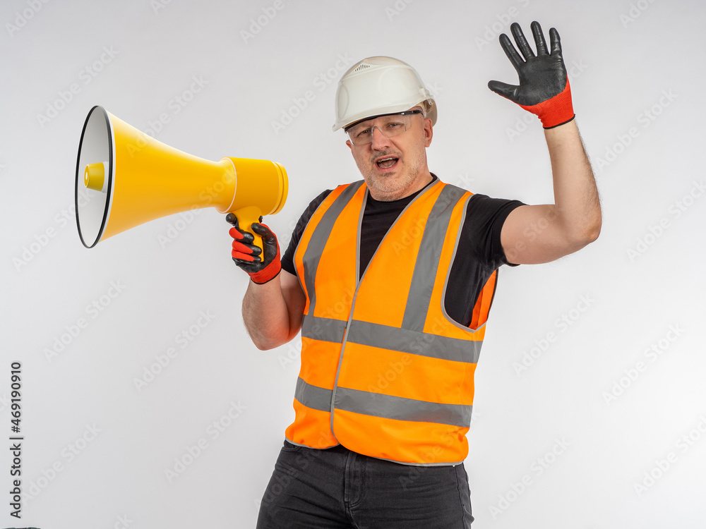 Builder with loudspeaker. Portrait of builder on light background. Man builder shouts into loudspeaker. Construction company advertising and marketing concept. Foreman makes stop gesture Builder with loudspeaker. Portrait of builder on light background. Man builder shouts into loudspeaker. Construction company advertising and marketing concept. Foreman makes stop gesture