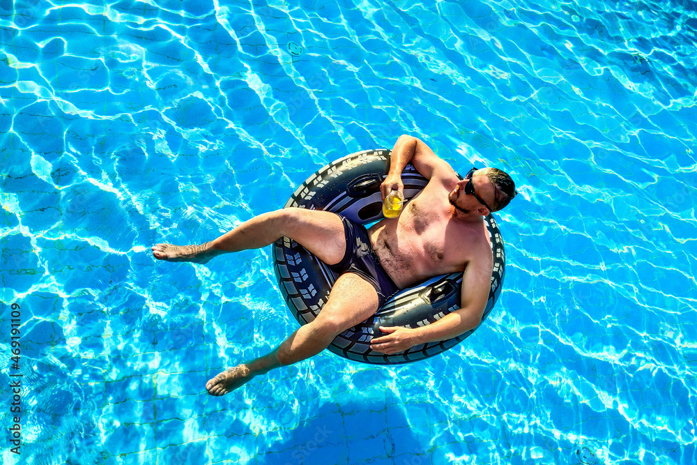 Pleasant man drinking cocktail in the pool. vacation concept Top view