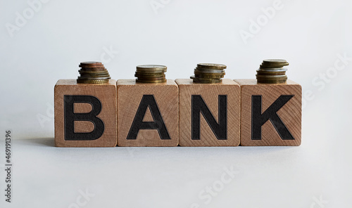 BANK inscription on wooden cubes, together with coins, isolated on white background, business and finance concept.
