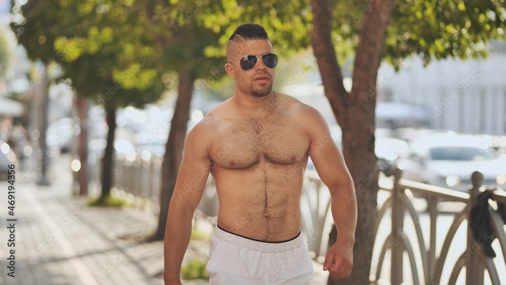A muscular Jordanian man walks around the city without a shirt. A muscular Jordanian man walks around the city without a shirt.