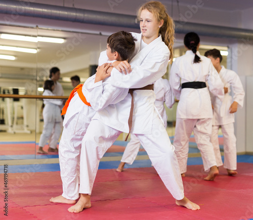 Boy and girl sparring together during group karate training in gym.
