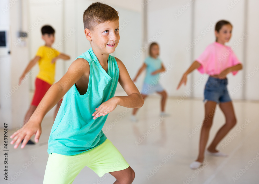 Young boy performing modern dance with his friends in studio during rehearsal.