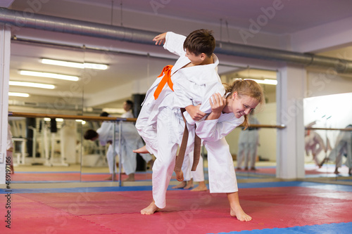 Sporty teenager children practicing new self defense moves in pairs at sport gym