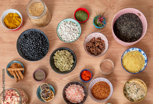 Set of bowls filled with all kinds of seasonings and legumes seen from the top