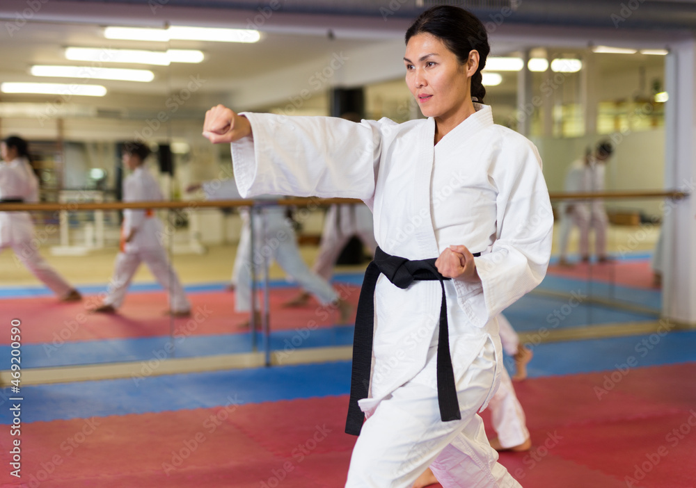 Portrait of asian female instructor wearing white kimono during training in gym