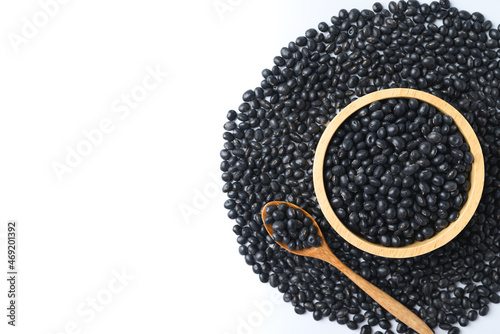 Black soy bean seeds in a wooden bowl with spoon on white background