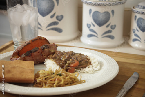 Sunday dinner with crock pot cooked beef stew white rice Asian noodles sweet potatoes and southern style corn bread