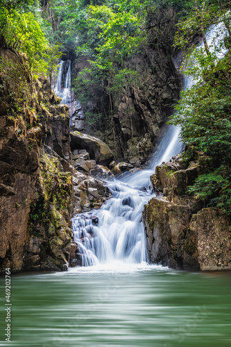 waterfall over rock and green tree with green small lake