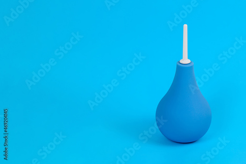 Blue pear-shaped enema with white tip on light blue background, copy space. Colon cleansing concept. Background for medical announcement