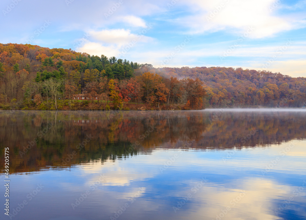 A country house on raccoon lake amidst beautiful Autumn colored trees during morning time.