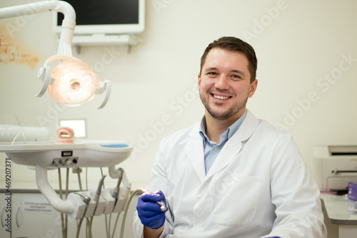 Male dentist smiling and holding tools in his hands. High quality photo
