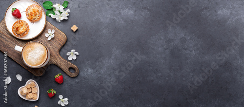 Delicious cake, coffee, fresh berry and spring flowers on dark stone background. Horizontal banner. Top view
