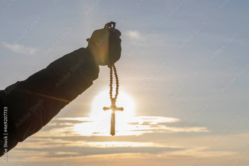 Silhouette Human hand holding Christian cross with sunset background ...