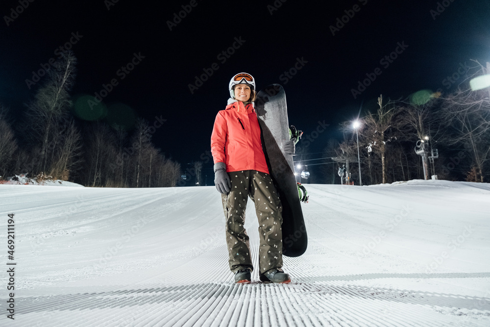 Portrait of female snowboarder at evening slope. Winter sports concept
