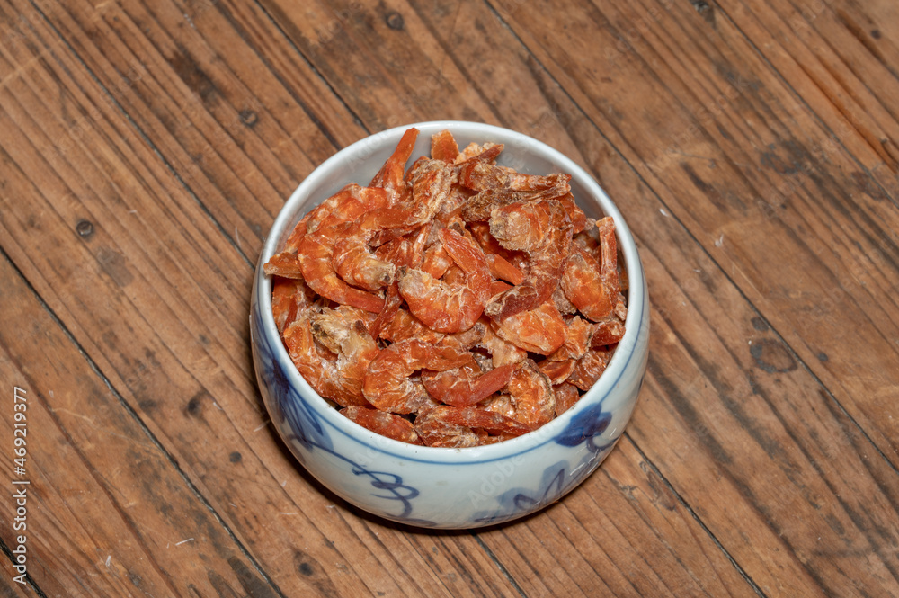 Shelled fresh shrimps on a plate or bowl are on a wood colored table Shelled fresh shrimps on a plate or bowl are on a wood colored table