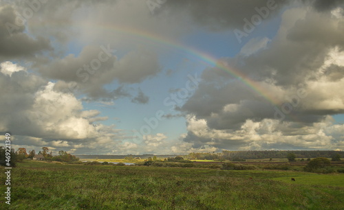 Meadow with clouds and rainbow.