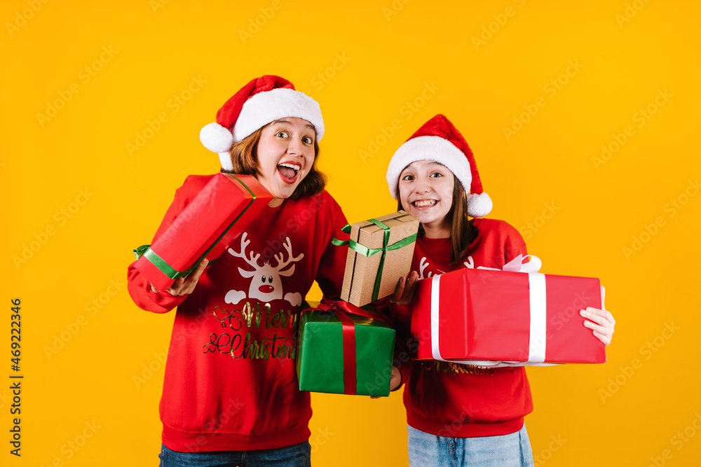 Portrait of Latin sisters girls holding Christmas gift box on a yellow background in Mexico latin america Portrait of Latin sisters girls holding Christmas gift box on a yellow background in Mexico latin america