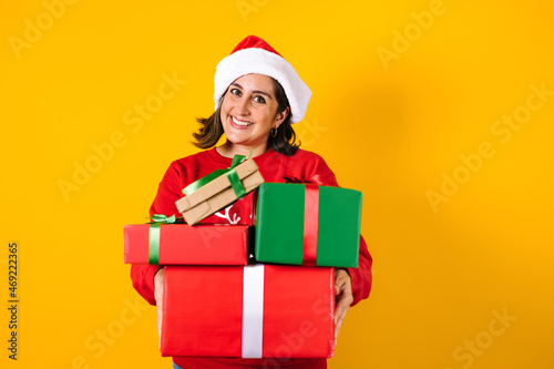 Portrait of Latin adult woman holding Christmas gift box on a yellow background in Mexico latin america