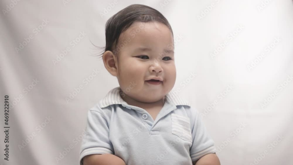 !-year-old Baby Boy Smiles While Sitting Against White Background In Studio. medium shot !-year-old Baby Boy Smiles While Sitting Against White Background In Studio. medium shot