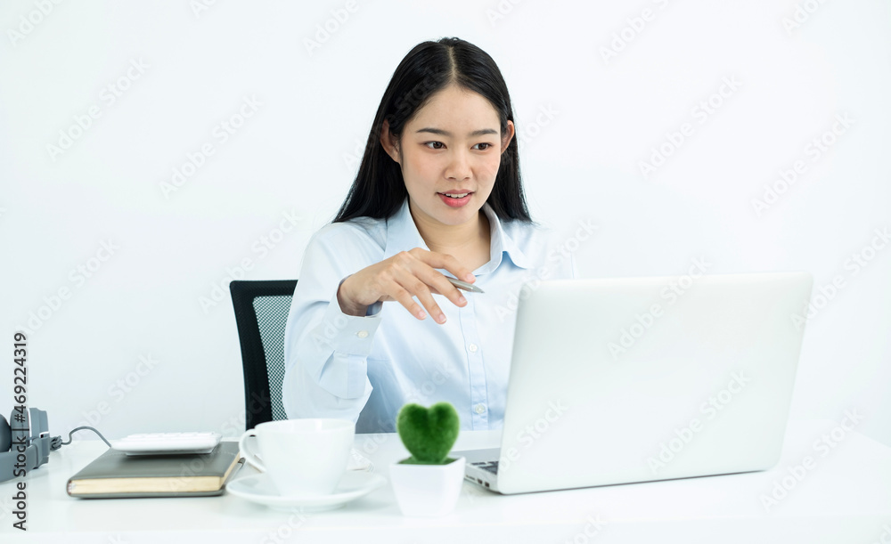Asian woman working on a laptop with a cheerful and happy smile while working and taking notes at the office Asian woman working on a laptop with a cheerful and happy smile while working and taking notes at the office