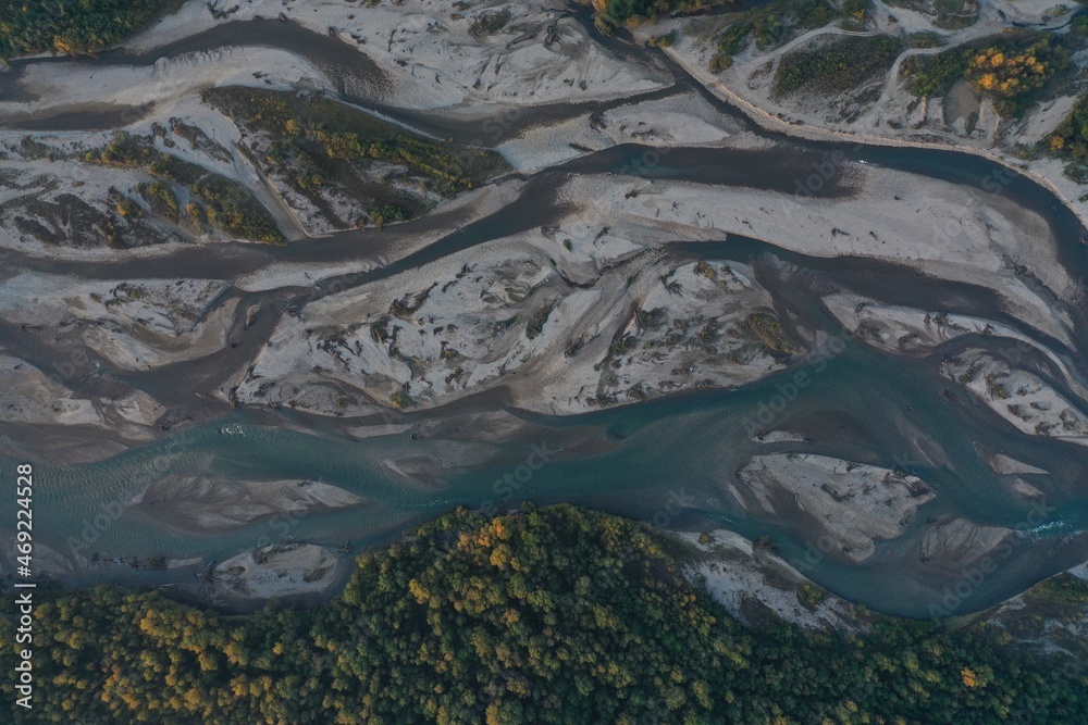 Aerial view of Laba river valley at dawn in autumn, Mostovskoy, Krasnodar Krai, Russia. Picturesque landscape, nature of Caucasus from drone. River flood, orange trees, stony coast snowy shore.