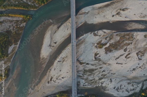 Aerial view of bridge road with cars over Laba river at sunrise in autumn, Mostovskoy, Krasnodar Krai, Russia. Picturesque landscape, nature of Caucasus. River flood, golden trees, stony coast. Trip photo