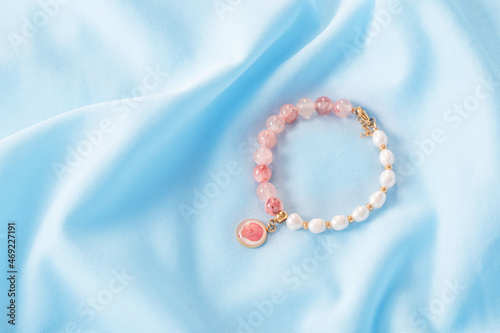 pink and white bracelet made of natural stones on blue silk fabric