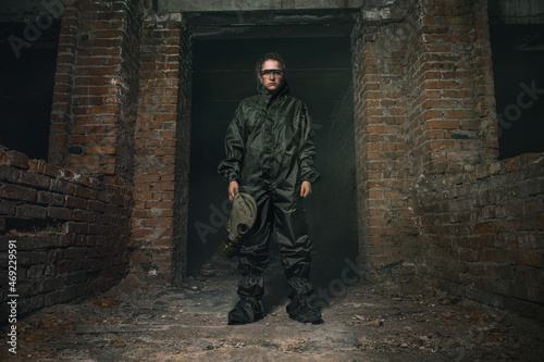Beautiful military girl. Portrait of a woman with a gas mask in a destroyed building. Post-apocalypse concept