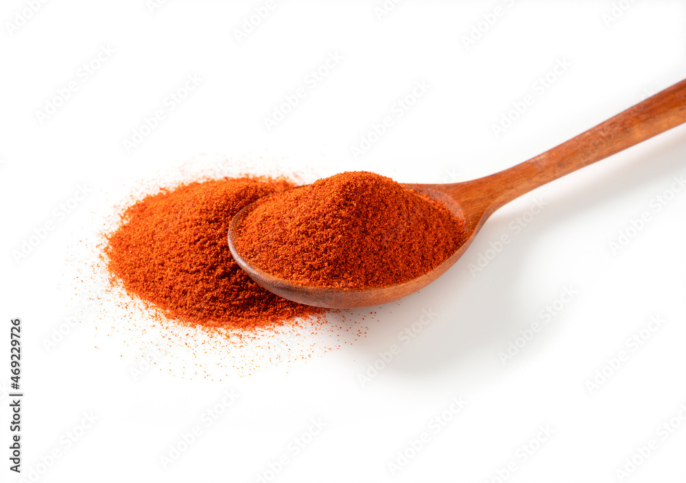 Red pepper powder and wooden spoon on a white background Red pepper powder and wooden spoon on a white background