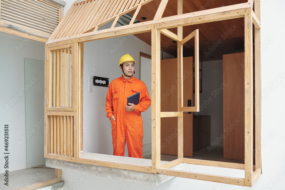 Vietnamese foreman in overall and hardhat checking house rennovation progress Vietnamese foreman in overall and hardhat checking house rennovation progress