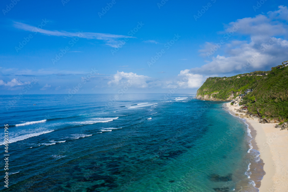 
Aerial drone landscape view of the white sand beach of Melasti located in South Bali in Indonesia, with tidal waves breaking along the shoreline.