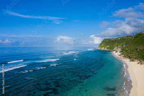  Aerial drone landscape view of the white sand beach of Melasti located in South Bali in Indonesia, with tidal waves breaking along the shoreline.