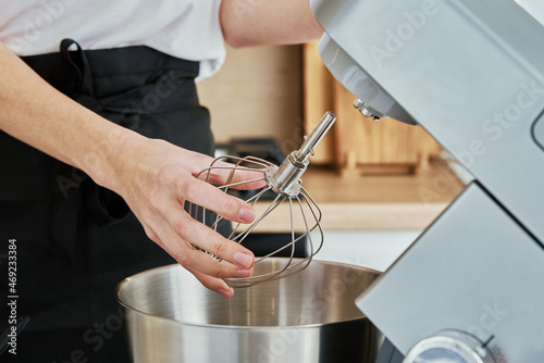 Woman put in whisk nozzle in electric mixer photo